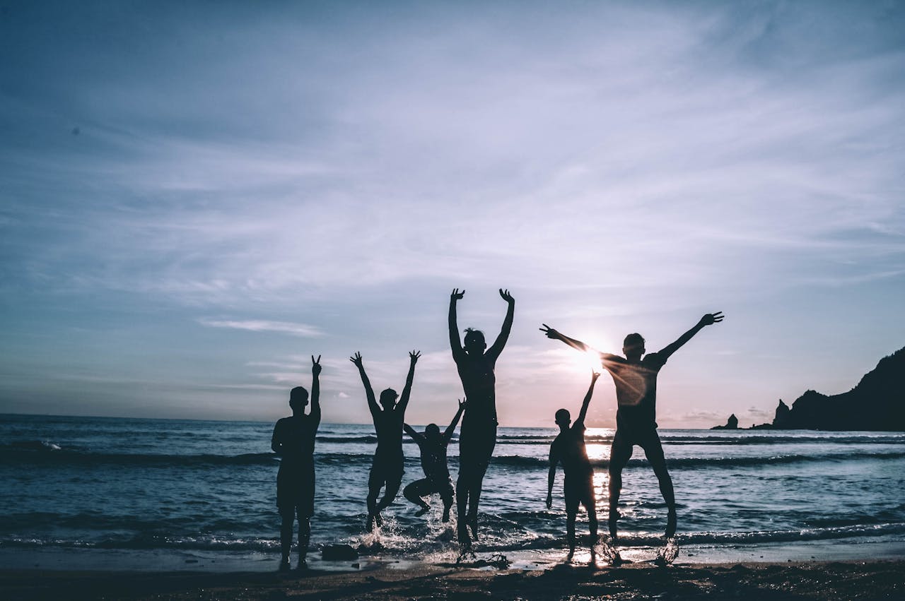 The Art of Drawing Readers In: Your attractive post title goes here Silhouetted group of friends jumping joyfully on the beach at sunset, symbolizing freedom and happiness.
